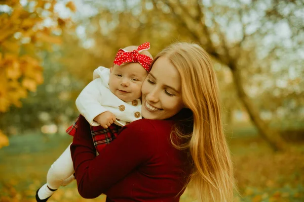 Anne ve kızı bir parkta sonbahar düşen yapraklar üzerinde güzel bir sonbahar günü zevk. Mutlu neşeli genç aile anne açık havada eğleniyor küçük bebeği ile. Uçan Bebek anne öpücüğü