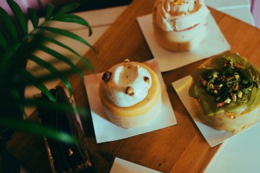 Pembe arka plandaki bir kalasın üzerindeki fırından gelen çeşitli tatlılar. Diyet ve tatlılar. Bir sürü lezzetli tatlı, güzel yuvarlak renkli pastalar.