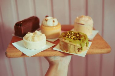 Pembe arka plandaki bir kalasın üzerindeki fırından gelen çeşitli tatlılar. Diyet ve tatlılar. Bir sürü lezzetli tatlı, güzel yuvarlak renkli pastalar.