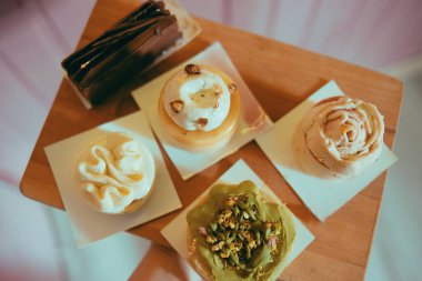 Pembe arka plandaki bir kalasın üzerindeki fırından gelen çeşitli tatlılar. Diyet ve tatlılar. Bir sürü lezzetli tatlı, güzel yuvarlak renkli pastalar.