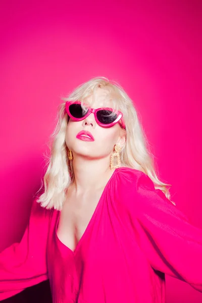 Ξανθιά Ποζάρει Ροζ Φόντο Κομψά Ροζ Γυαλιά Και Φόρεμα Κορίτσι — Φωτογραφία Αρχείου