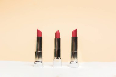 Ruj farklı renkler, güneş gözlüğü seçenekleri. Çıplak arka planda kozmetik ürünleri. Güzel ruj örnekleri, pembe ve kırmızı.