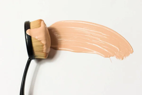 白い背景に顔にファンデーションを塗るためのブラシ ファンデーション ブラシに流れる化粧品 パーソナルケア メイク スマッジ製品の色 — ストック写真