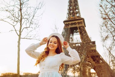 Paris 'te Eyfel Kulesi' nin arka planında bereli beyaz elbisesi olan güzel bir sarışın. Kadın gülüyor, gülüyor, kız Fransa 'ya seyahate gitti..