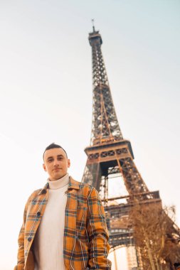 Eyfel Kulesi 'nin arka planındaki adam poz veriyor. Erkek turistler güler ve gülümser. # Yolculukta yakışıklı esmer #.