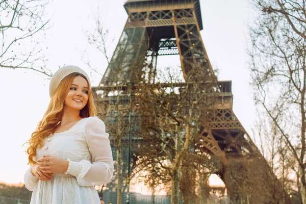 一个站在巴黎埃菲尔铁塔后面的女孩 戴着贝雷帽 头戴卷发的裙子 这是一段浪漫的旅程 女人又笑又看 — 图库照片