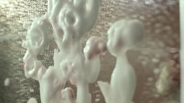 Glass cleaner splashes on a mirror on which there is an inscription with lipstick. Cleaning