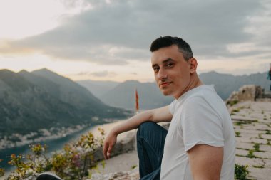 Karadağ 'da bir dağın tepesindeki adam, Kotor. Denizin ve dağların arkasındaki adam taşların üzerinde dinleniyor. Avrupa 'da seyahat