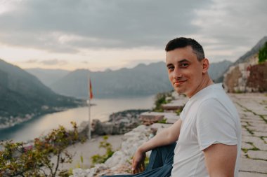 Karadağ 'da bir dağın tepesindeki adam, Kotor. Denizin ve dağların arkasındaki adam taşların üzerinde dinleniyor. Avrupa 'da seyahat