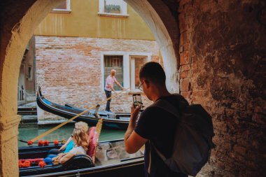 A man stands near the Grand Canal in Venice, a tourist with a backpack takes a photo on the phone