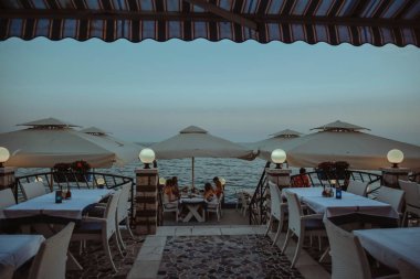 Photo of the restaurant on the background of the sea. Dinner, evening dark photo. Rest and food