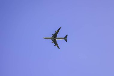 The plane flies against the blue sky. Travels