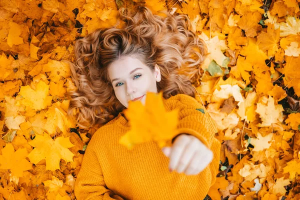 少女は秋の葉の中にあり カメラに1つを保持し 10代の良い秋の写真 — ストック写真