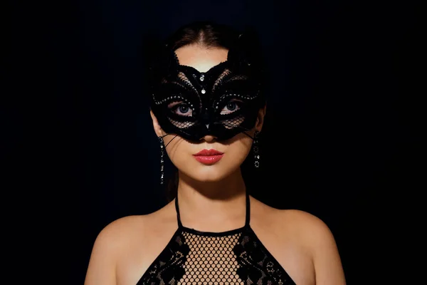 The girl in the mask. Masquerade, halloween. Girl in a cat mask. Catwoman on a beautiful background in a beautiful lace top with long earrings