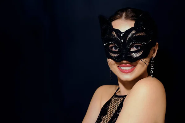 The girl in the mask. Masquerade, halloween. Girl in a cat mask. Catwoman on a beautiful background in a beautiful lace top with long earrings