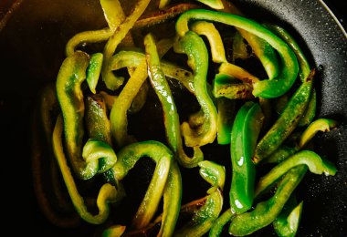 Güzel yeşil biberler bir olii üzerinde kızartma tavasında kızartılır. Sağlıklı yemekler, kızarmış sebzeler.