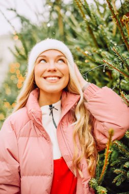 Şirin bir sarışın yeni yıl için bir Noel ağacı seçer. Karlı havada şapkalı ve pembe ceketli bir kadın kameraya gülümsüyor. Kış tatili ve yeni yıl