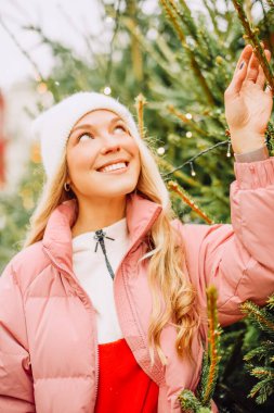 Şirin bir sarışın yeni yıl için bir Noel ağacı seçer. Karlı havada şapkalı ve pembe ceketli bir kadın kameraya gülümsüyor. Kış tatili ve yeni yıl