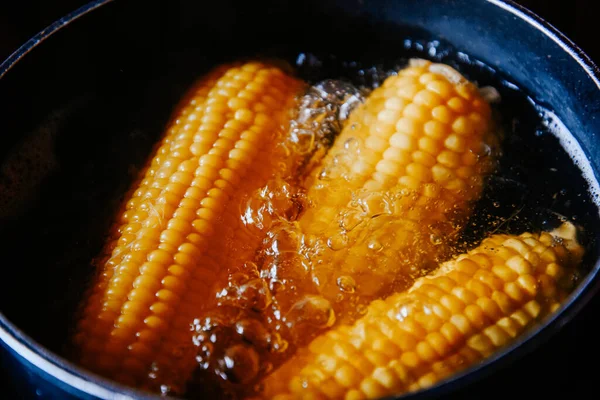 Orange juicy corn is boiled in water with salt. Corn in boiling water in a saucepan. Healthy food at home