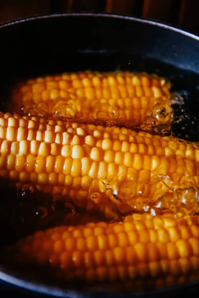 Orange juicy corn is boiled in water with salt. Corn in boiling water in a saucepan. Healthy food and vegetables