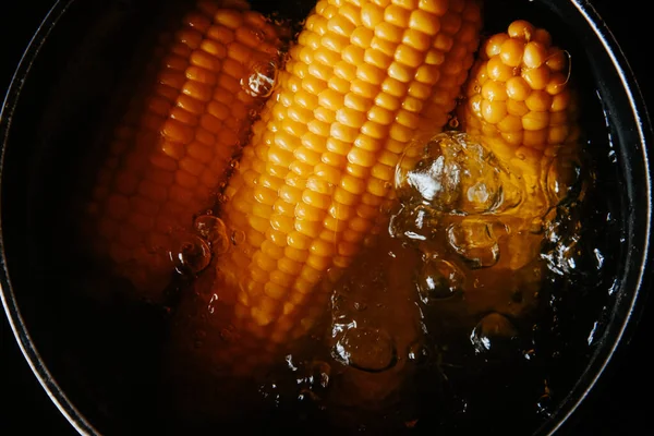 Orange juicy corn is boiled in water with salt. Corn in boiling water in a saucepan. Healthy food at home