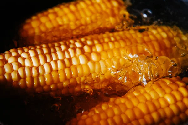 Orange juicy corn is boiled in water with salt. Corn in boiling water in a saucepan. Healthy food and vegetables