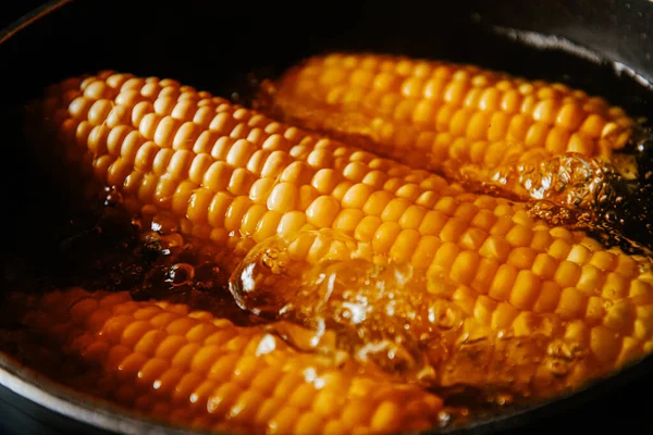 Orange juicy corn is boiled in water with salt. Corn in boiling water in a saucepan