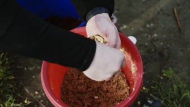 Erkek eller oltaya yem takar ve çimin arka planına kanca takar. Balıkçılık Yem ile doludur