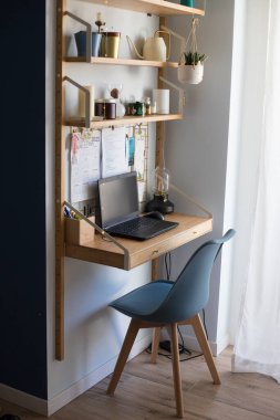 Küçük ofis uzaktan kumanda istasyonu, çalışma alanı, dizüstü bilgisayarı, ev bitkileri, metal tahta, mumlar ve masa lambası. Dikey çekim. Yan görünüm.