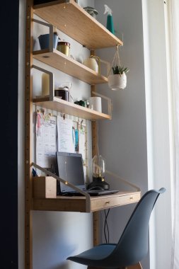 Küçük ofis uzaktan kumanda istasyonu, çalışma alanı, dizüstü bilgisayarı, ev bitkileri, metal tahta, mumlar ve masa lambası. Dikey çekim. Yan görünüm.
