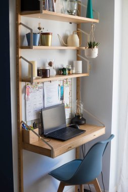 Küçük ofis uzaktan kumanda istasyonu, çalışma alanı, dizüstü bilgisayarı, ev bitkileri, metal tahta, mumlar ve masa lambası. Dikey çekim. Yan görünüm.