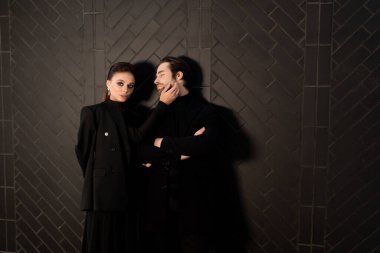 Siyah takım elbiseli genç bir çift ve koyu bir arka planda ceket.