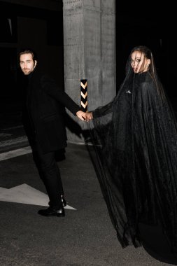 Şehrin arka planında sırt çantalı siyah elbiseli genç bir çift.