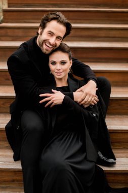 Genç ve güzel bir çift ahşap bir bankta poz veriyor.