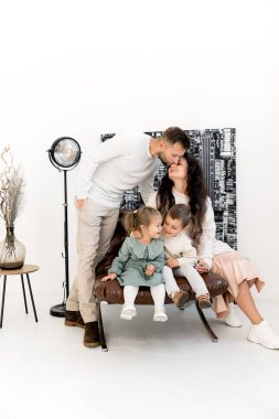 Evde çocukları olan mutlu bir aile. Erkek kadını öpüyor  