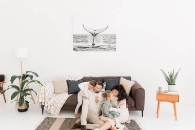 Mutlu genç aile evde yerde oturuyor. 
