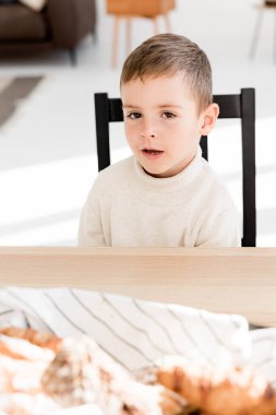 Evdeki masada oturan küçük tatlı çocuk. 