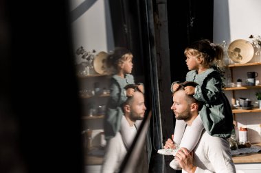 Genç baba ve kızı pencerenin önünde dikiliyorlar. 