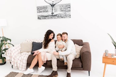 Mutlu bir aile ve oğlu kanepede poz veriyor. 