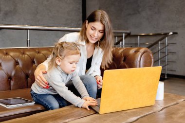 Anne ve kızı laptopa bakıyor.