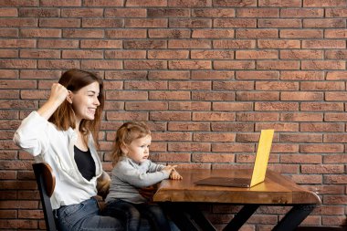 Anne ve kızı oturmuş laptopa bakıyorlar.