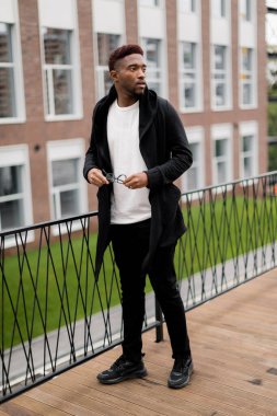 Dışarıda poz veren yakışıklı, Afro-Amerikan bir adamın portresi.