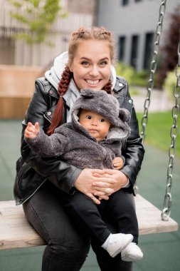 Salıncakta oğlu olan genç bir anne. 