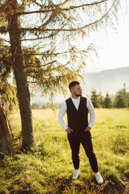 Yakışıklı genç damat doğada poz veriyor.