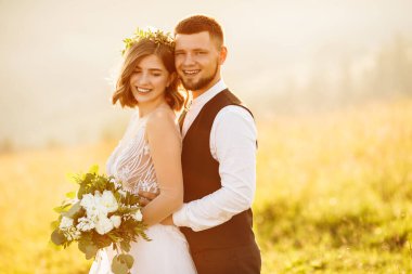 Güzel gelin ve damat doğaya sarılıyor.