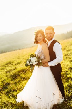 Güzel gelin ve damat doğaya sarılıyor.