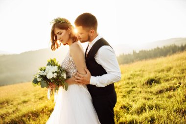 Güzel gelin ve damat doğaya sarılıyor.