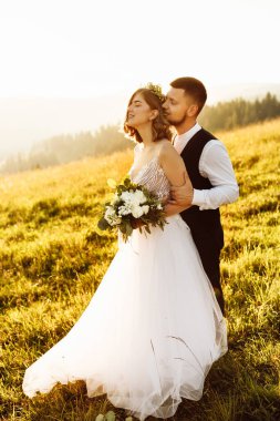 Güzel gelin ve damat doğaya sarılıyor.