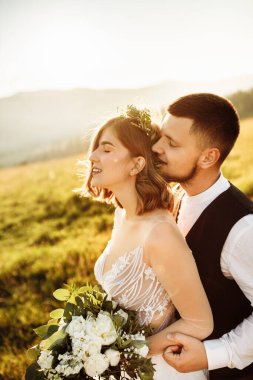 Güzel gelin ve damat doğaya sarılıyor.