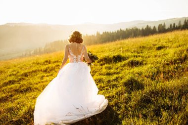 Doğaya poz veren beyaz elbiseli güzel gelin
